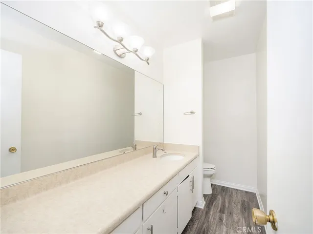 a spacious bathroom with a granite countertop sink a toilet and a mirror