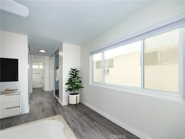 a view of an empty room with a window and wooden floor