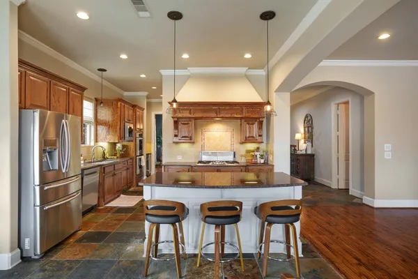a kitchen with stainless steel appliances kitchen island granite countertop a refrigerator and a stove top oven