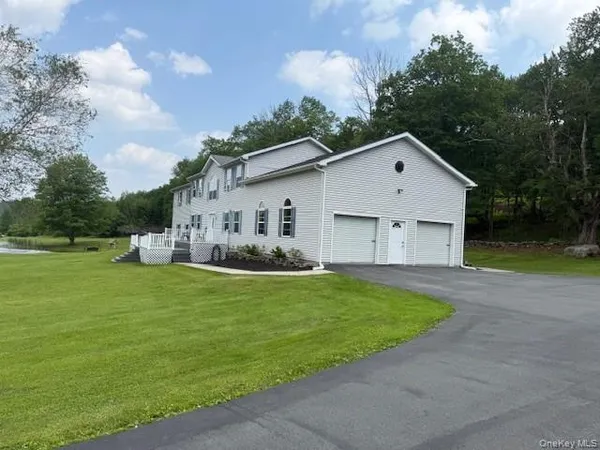 a view of a white house with a big yard plants and large trees