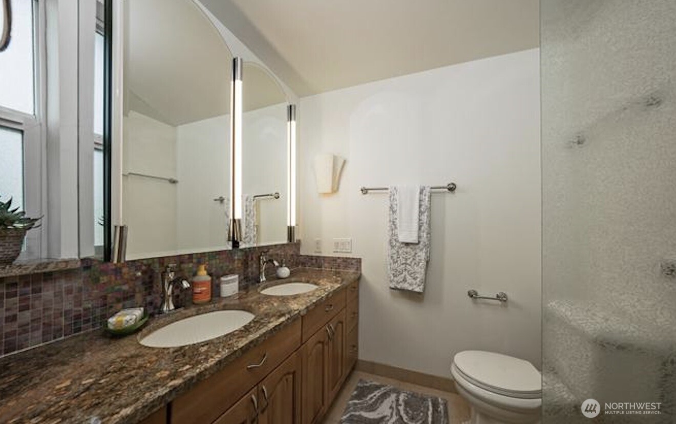 617 West Mercer Place, Unit 401 Seattle, WA 98119 - Photo 13 of 15 a bathroom with a granite countertop sink toilet a mirror and shower