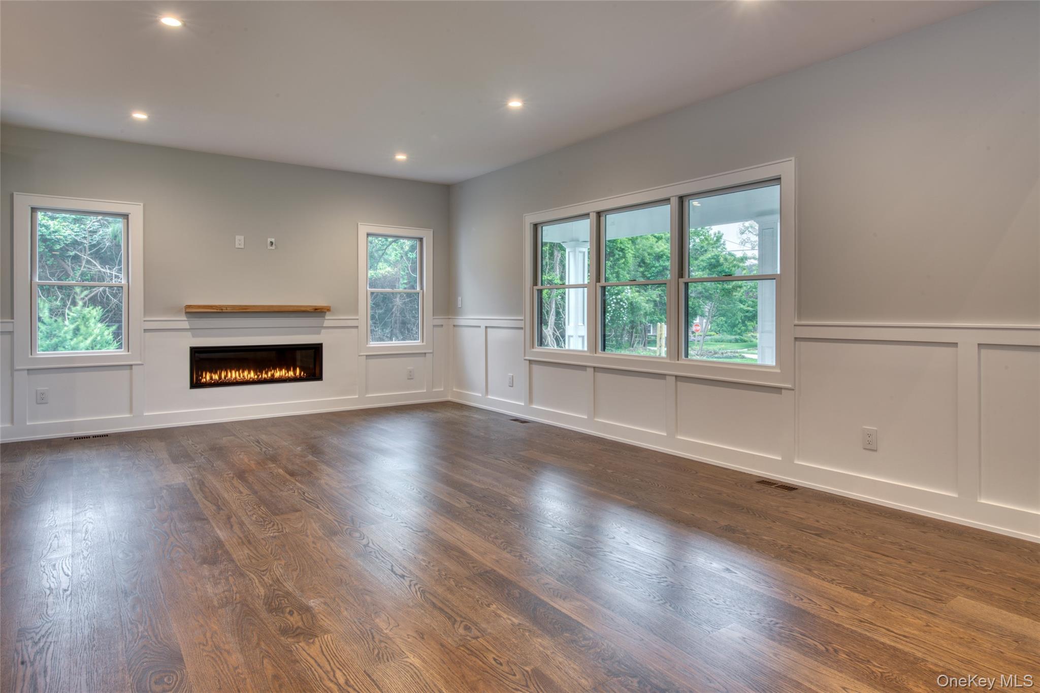 435 Maple Lane Greenport, NY 11944 - Photo 12 of 44 an empty room with wooden floor fireplace and windows