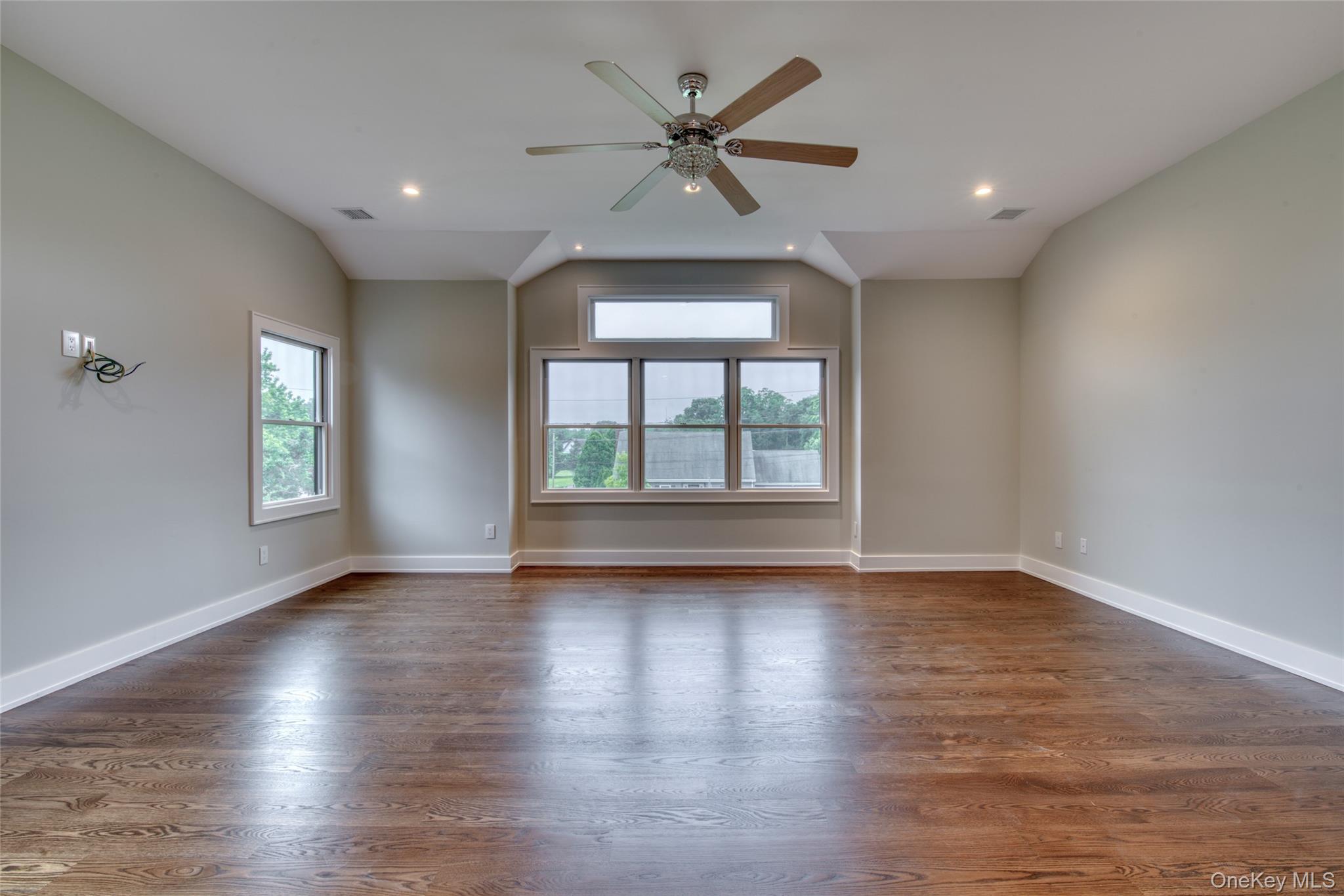 435 Maple Lane Greenport, NY 11944 - Photo 21 of 44 an empty room with wooden floor chandelier fan and windows
