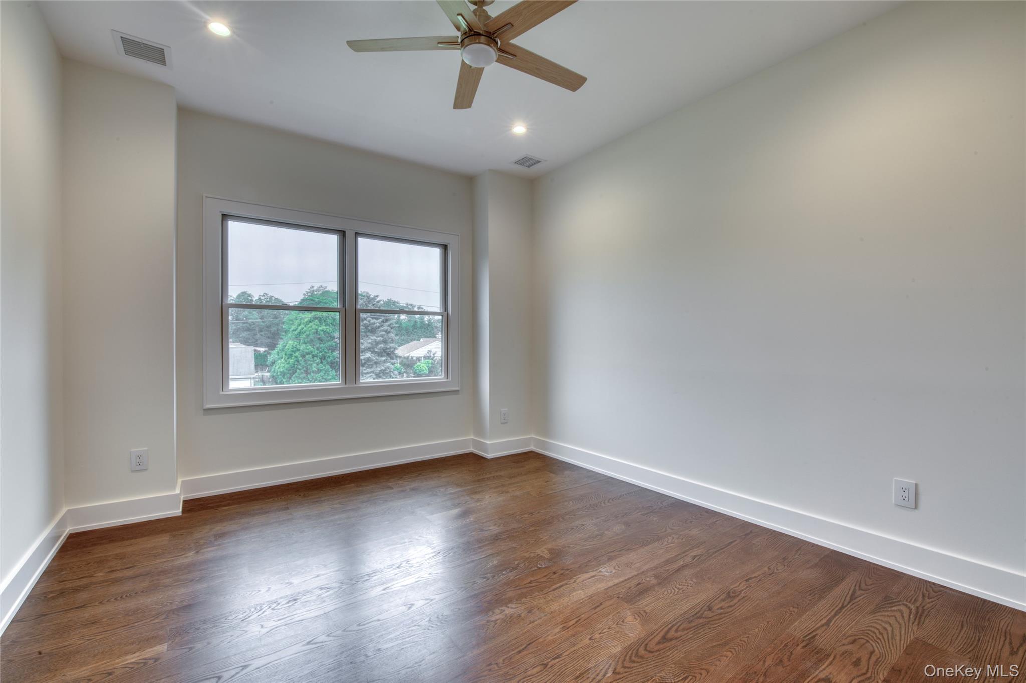 435 Maple Lane Greenport, NY 11944 - Photo 35 of 44 an empty room with wooden floor chandelier fan and windows