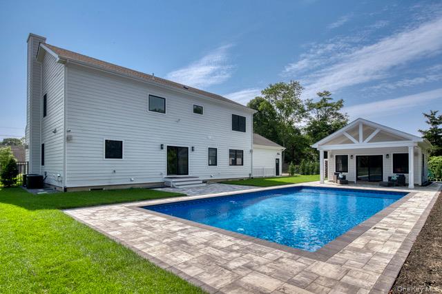 435 Maple Lane Greenport, NY 11944 - Photo 40 of 42 Rear view of house featuring a storage structure, an outdoor structure, an outdoor pool, and a patio