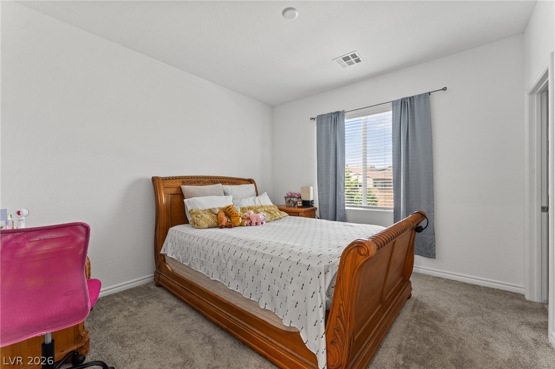 8879 Roadrunner Ravine Street Las Vegas, NV 89166 - Photo 31 of 39 A well-lit bedroom features plush carpeting and a large window providing natural light.