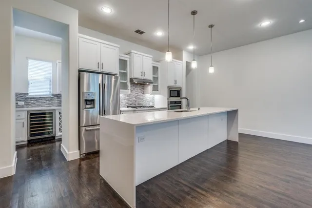 a large kitchen with stainless steel appliances a refrigerator and a wooden floor