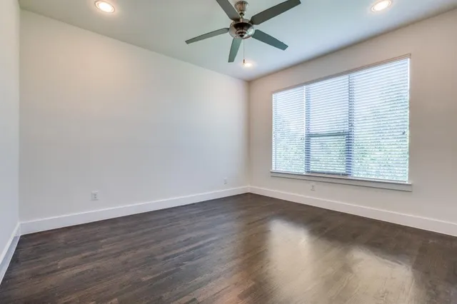 an empty room with wooden floor fan and windows