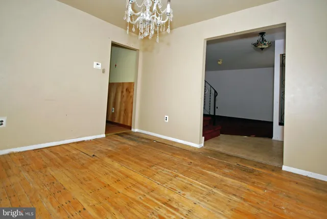 a view of an empty room with wooden floor and a chandelier