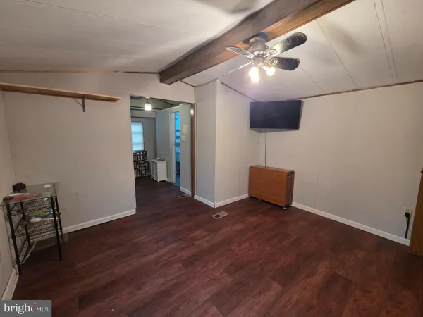 a view of an empty room with wooden floor and a ceiling fan