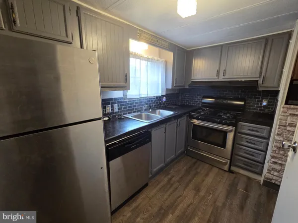 a kitchen with granite countertop a refrigerator stove and sink