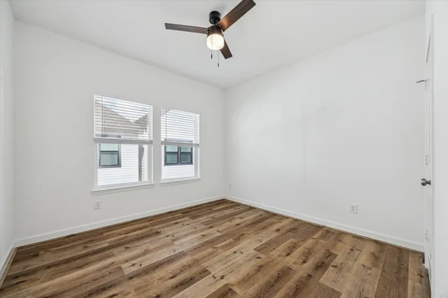 a view of empty room with wooden floor and fan