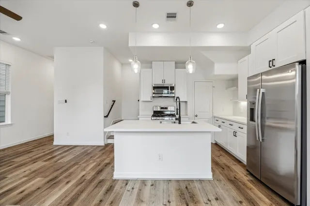 a kitchen with kitchen island a sink stainless steel appliances and cabinets