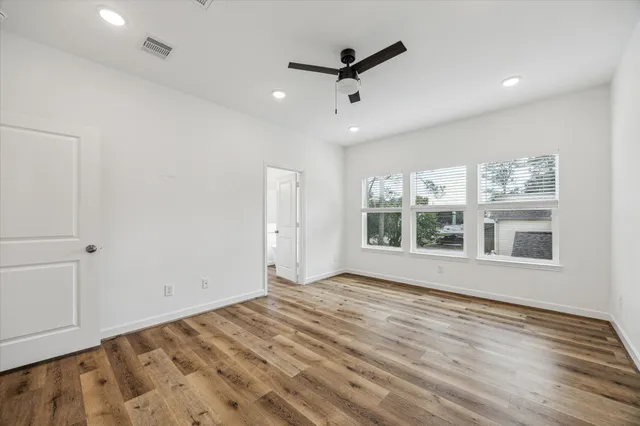 a view of an empty room with a window and wooden floor