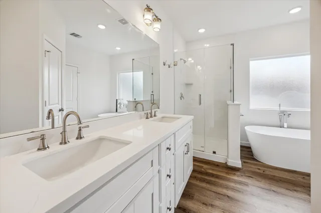 a bathroom with a double vanity sink a mirror and a bathtub