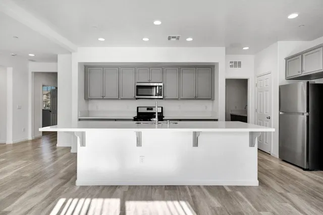 a large kitchen with stainless steel appliances a refrigerator and a stove top oven