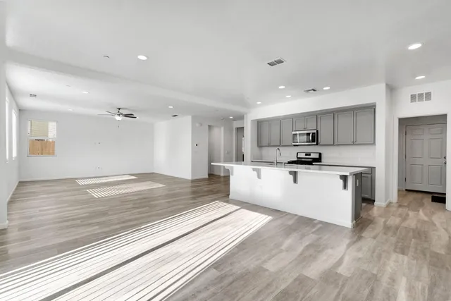 a large white kitchen with kitchen island a sink stainless steel appliances and cabinets