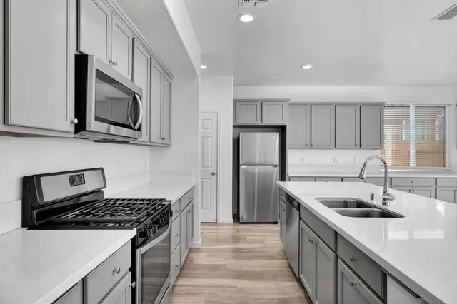a kitchen with stainless steel appliances granite countertop a sink stove microwave refrigerator and cabinets