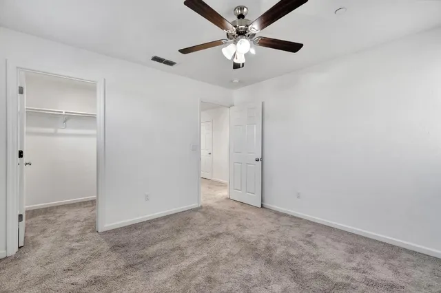 an empty room with a fan & a ceiling fan