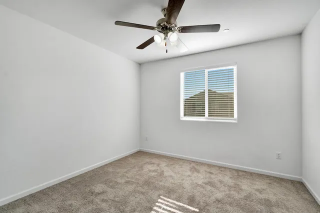 an empty room with a window and a ceiling fan