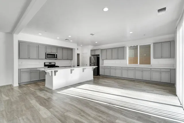 a large white kitchen with kitchen island a sink stainless steel appliances and cabinets