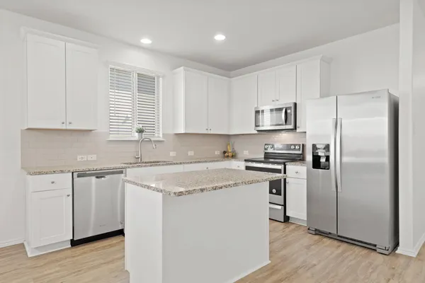 a kitchen with stainless steel appliances granite countertop a stove a sink and a refrigerator