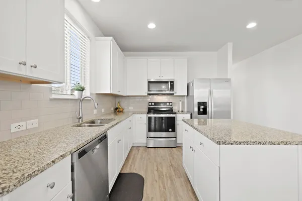 a kitchen with granite countertop a sink a counter space appliances and cabinets