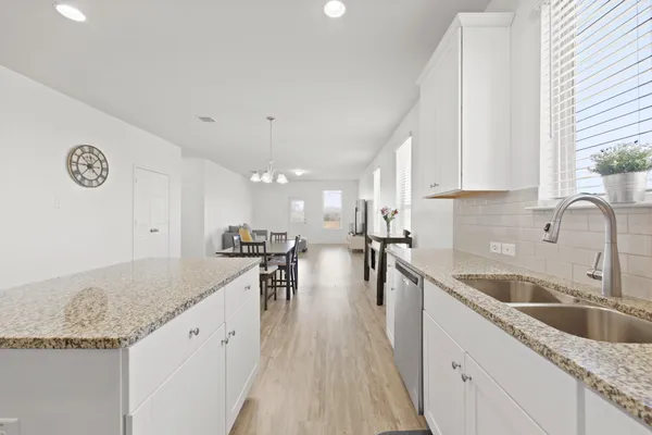 a kitchen with granite countertop a sink a counter top space and cabinets