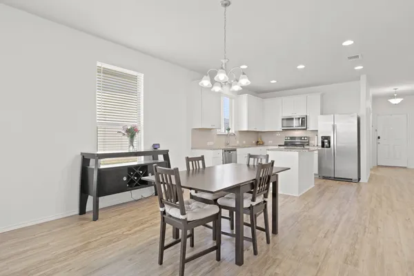 a kitchen with kitchen island a dining table chairs stainless steel appliances and cabinets