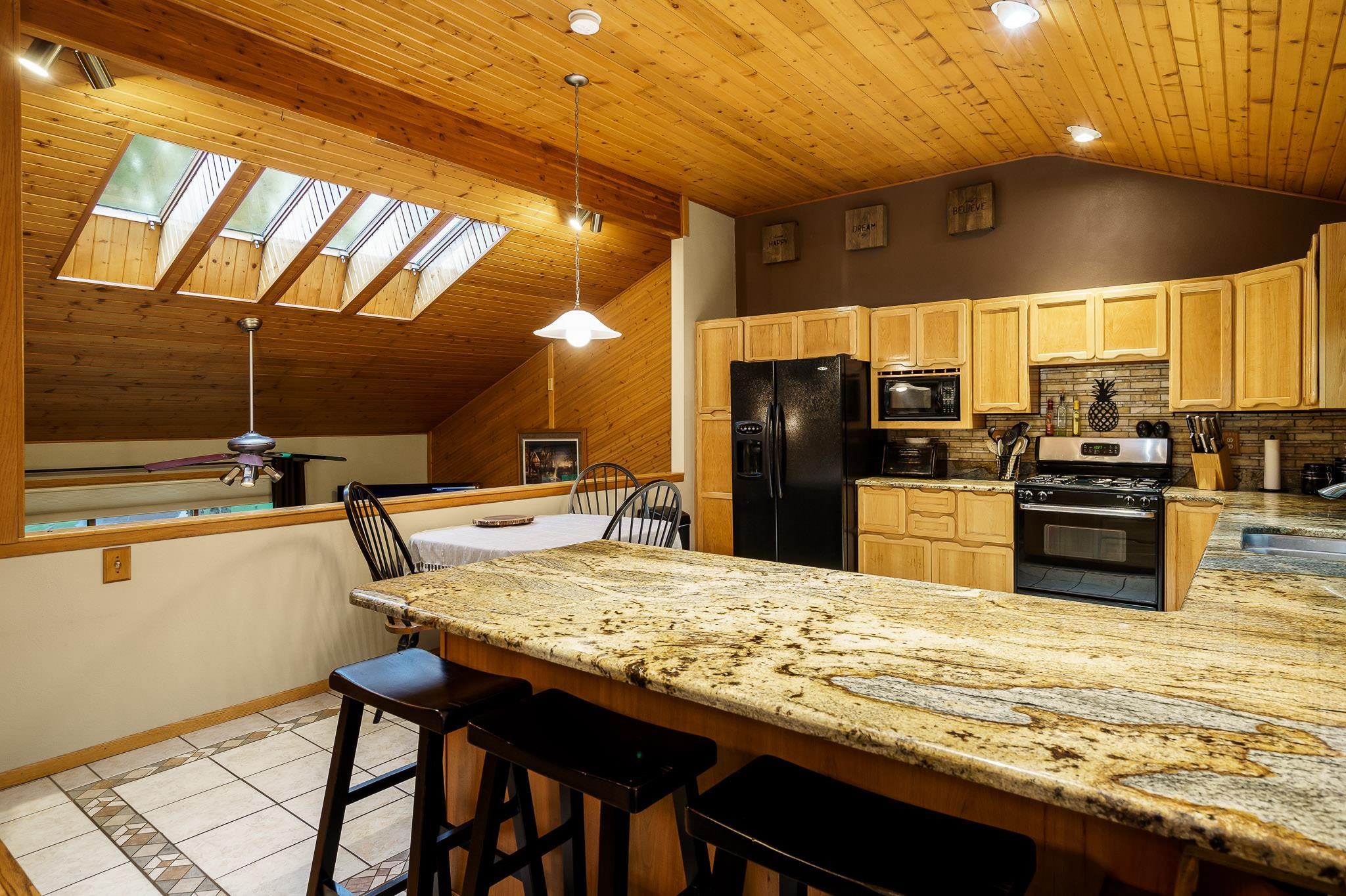 3942 Montclair Road Roscoe, IL 61073 - Photo 12 of 38 a kitchen with stainless steel appliances kitchen island granite countertop a table chairs and a refrigerator