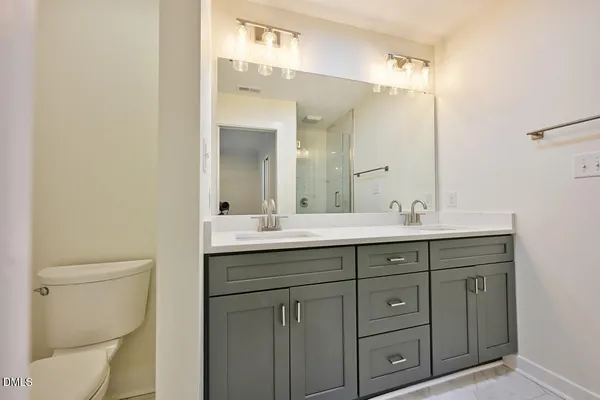 a bathroom with a double vanity sink toilet and a mirror