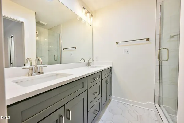 a bathroom with a double vanity sink a mirror and shower