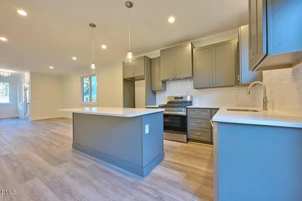a large kitchen with stainless steel appliances a large counter top a stove and a sink