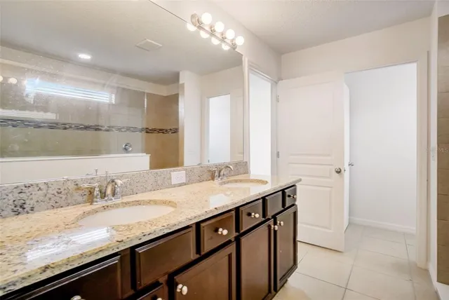 a bathroom with a granite countertop sink a vanity and a large mirror