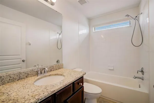 a bathroom with a granite countertop sink a toilet and shower