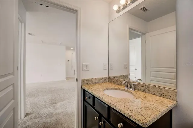 a bathroom with a granite countertop sink and a mirror