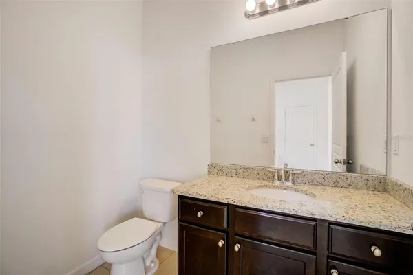 a bathroom with a granite countertop sink a toilet and a mirror