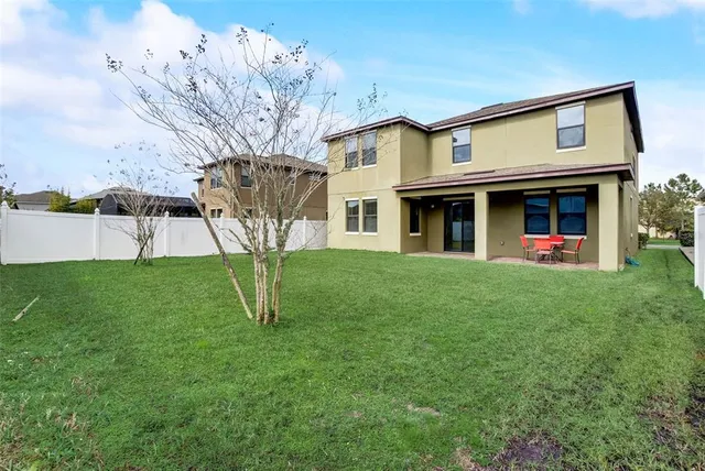 a view of an house with backyard and a tree