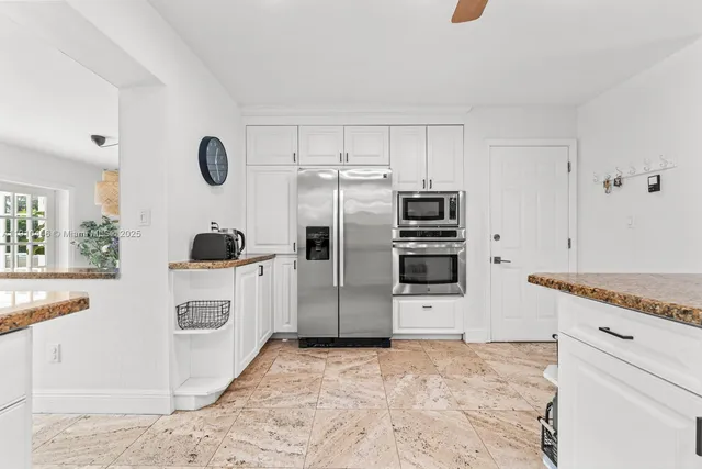 a kitchen with kitchen island granite countertop a sink a stove cabinets and a dining table