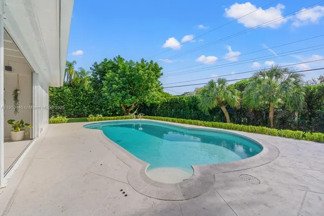 a view of a house with a big yard and palm trees