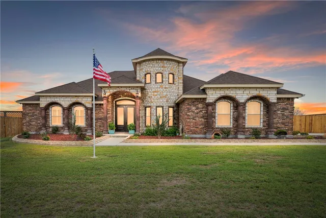 a front view of a house with garden and trees