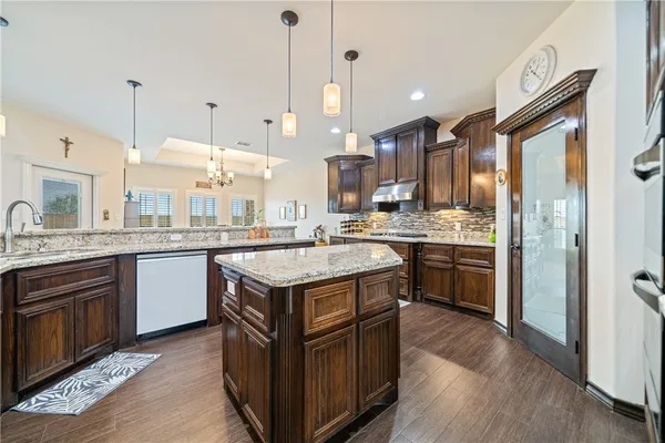 a kitchen with kitchen island granite countertop a sink a stove and a refrigerator