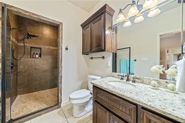 a bathroom with a granite countertop sink a toilet and shower