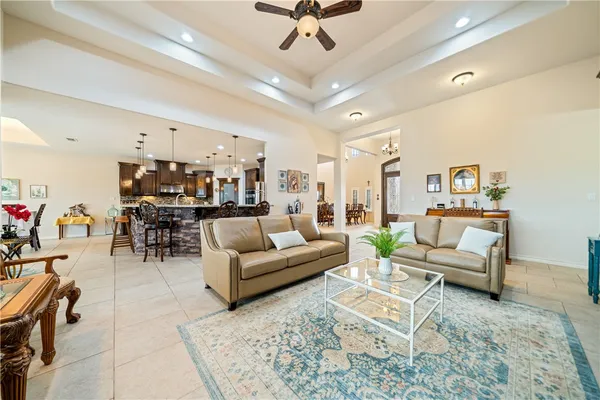 a living room with furniture kitchen view and a chandelier