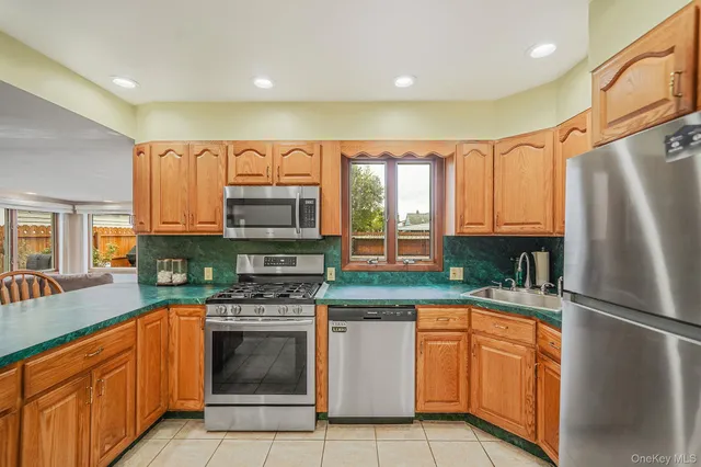 a kitchen with stainless steel appliances granite countertop a refrigerator a stove and a sink