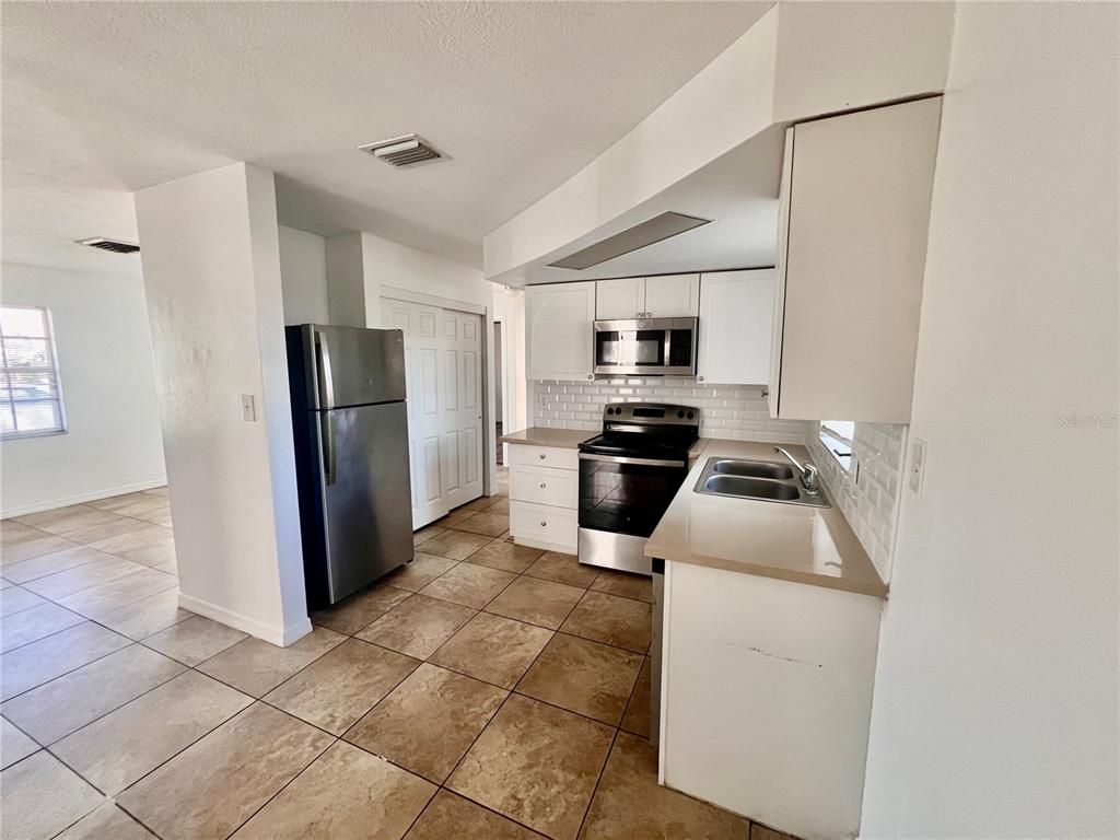 9504 Richwood Lane Port Richey, FL 34668 - Photo 6 of 16 a kitchen with a refrigerator a stove top oven and a sink
