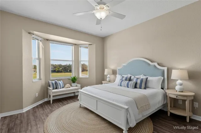a view of an empty room with wooden floor and a ceiling fan