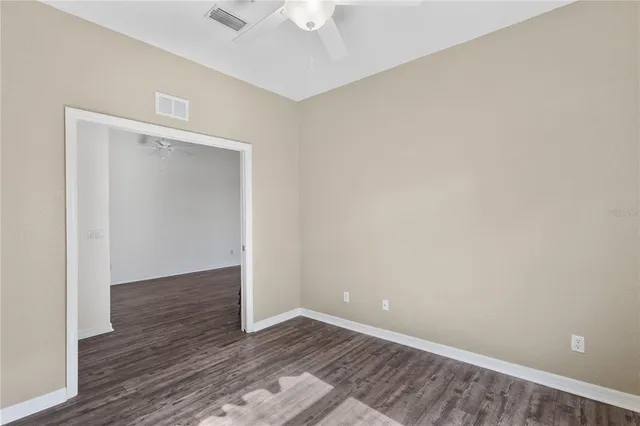 an empty room with wooden floor and ceiling fan