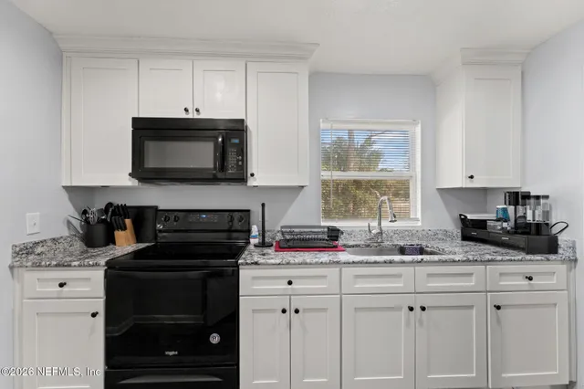 a kitchen with granite countertop white cabinets and black appliances