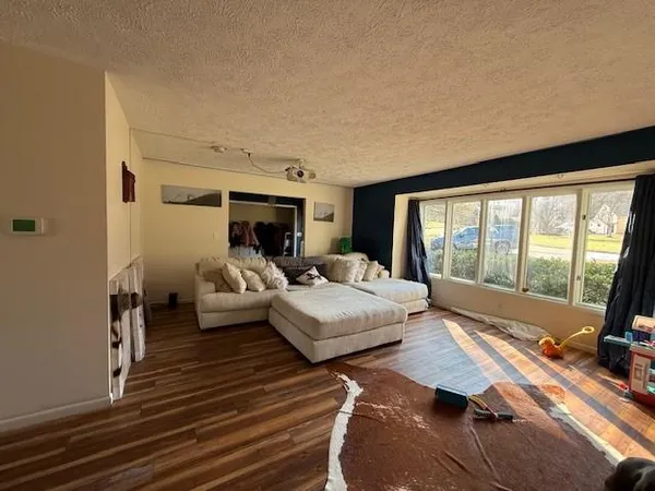 a living room with furniture large windows and wooden floor